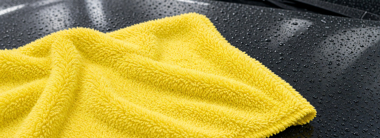 Lemon-yellow high-low plush microfiber towel on a wet car hood